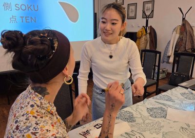 Lektorka Nanami uśmiecha się i udziela wskazówek uczestniczce warsztatów